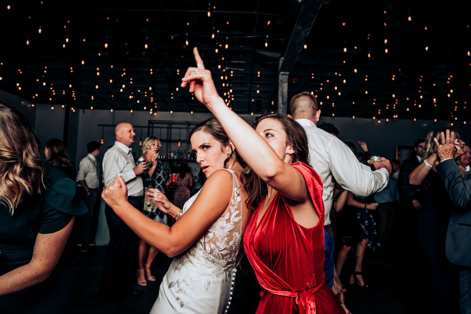 Guests dancing enthusiastically under a ceiling of sparkling lights at a celebration.