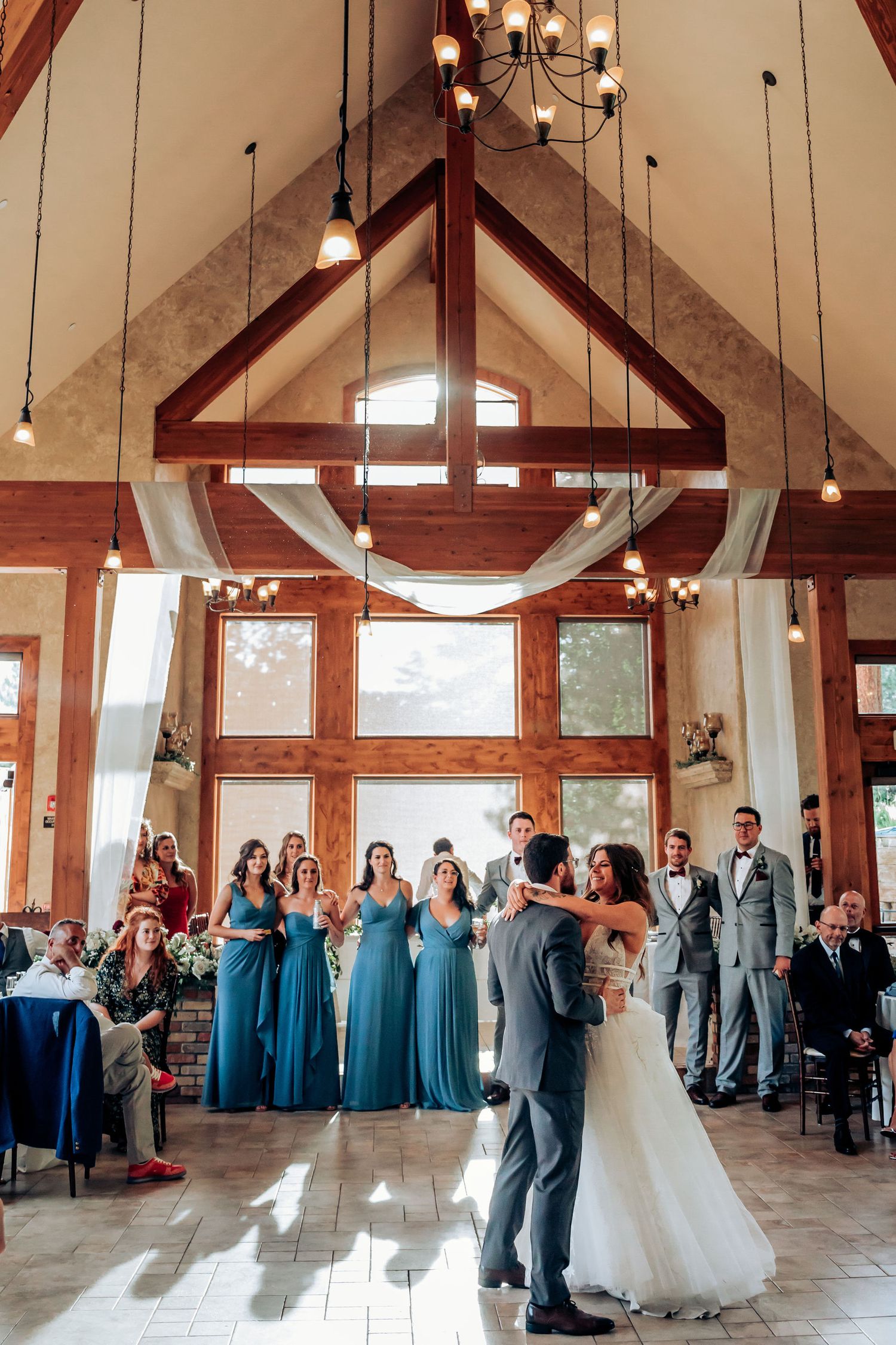 Wedding celebration in rustic venue with cathedral ceiling and pendant lighting.