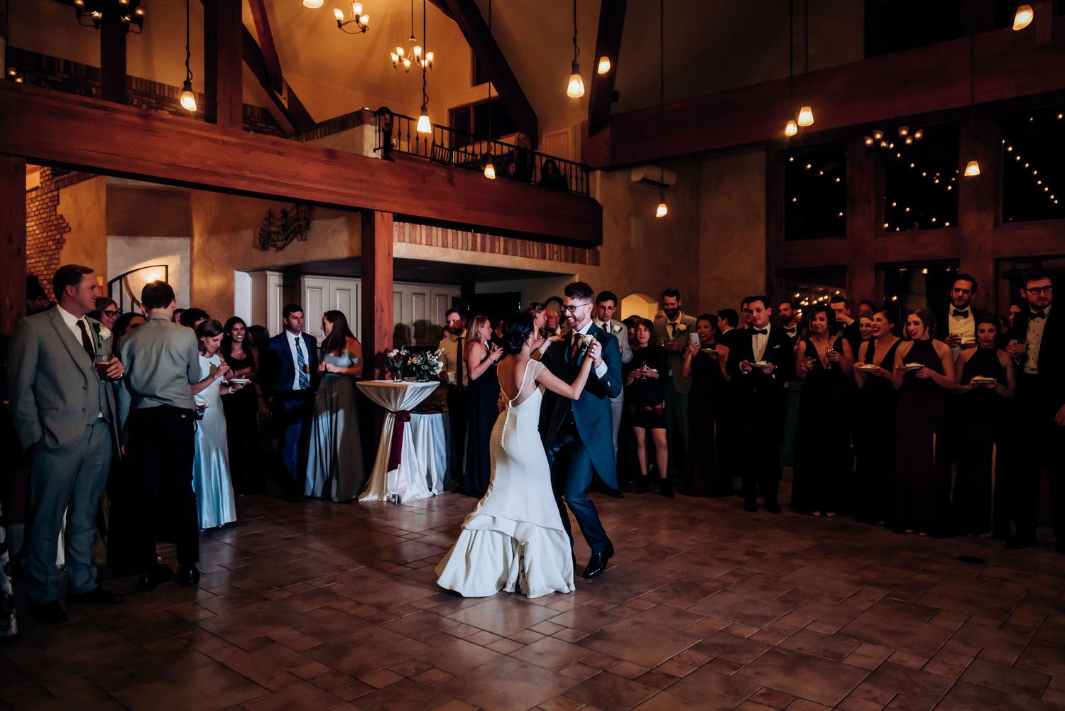 A wide shot of a wedding reception first dance with guests watching from the perimeter.