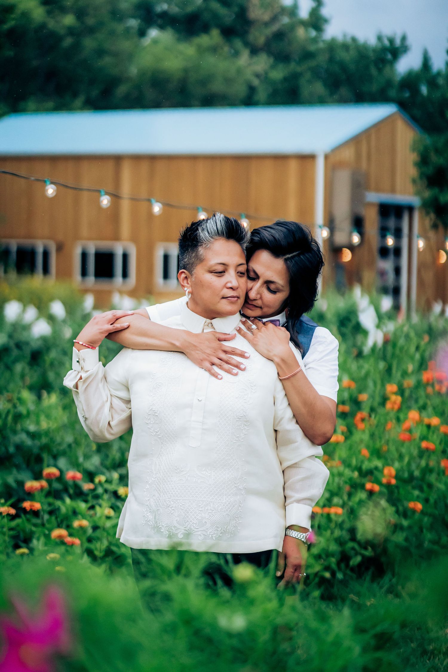 A loving couple sharing an intimate moment in a garden with string lights and flowers.