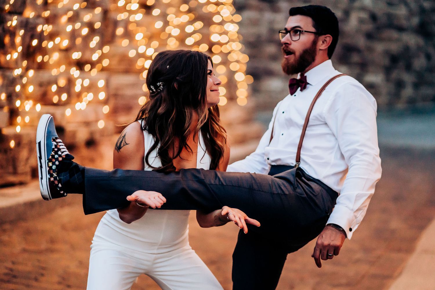 A playful moment captured with dancing and laughter against sparkling string lights.