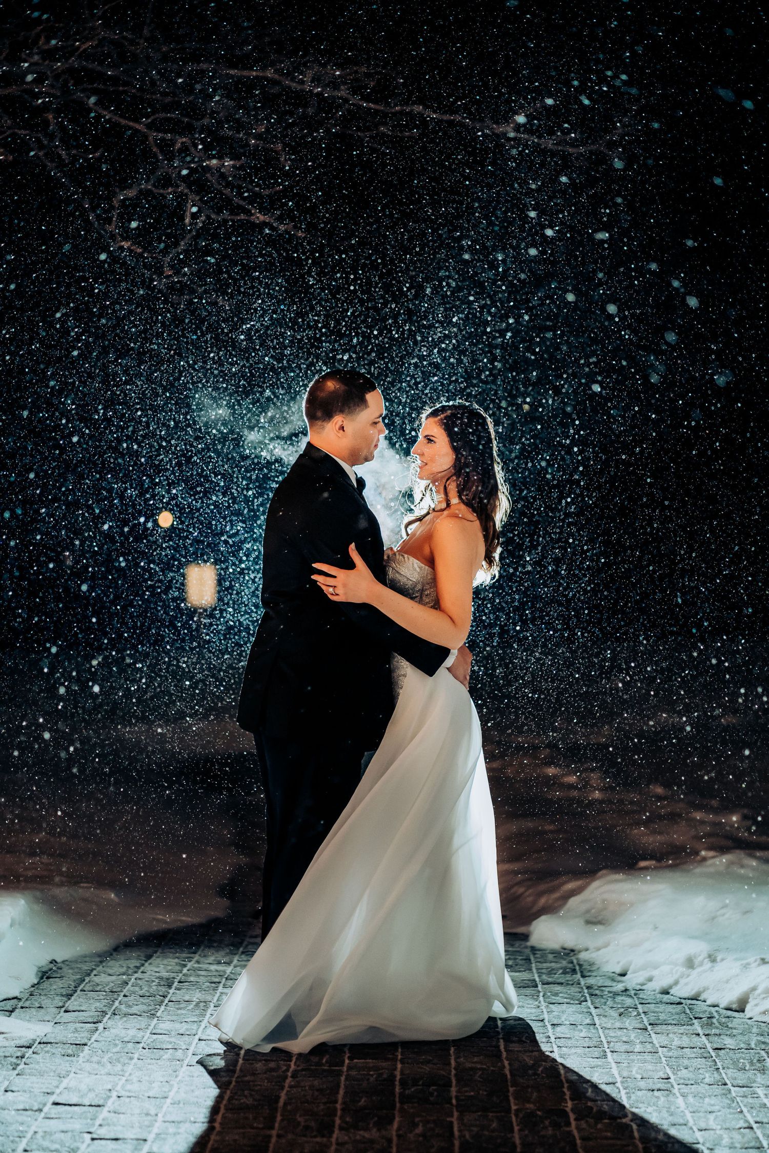 Romantic dance pose illuminated by twinkling lights in snowy evening setting.