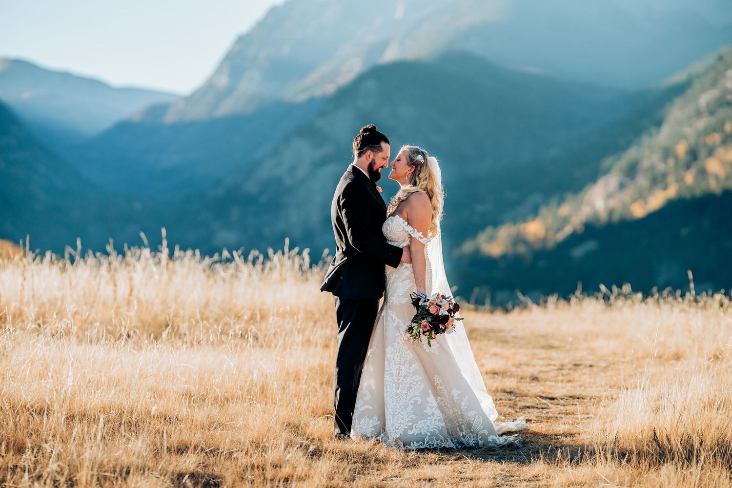 Wedding couple walking through golden mountain meadow at sunset.