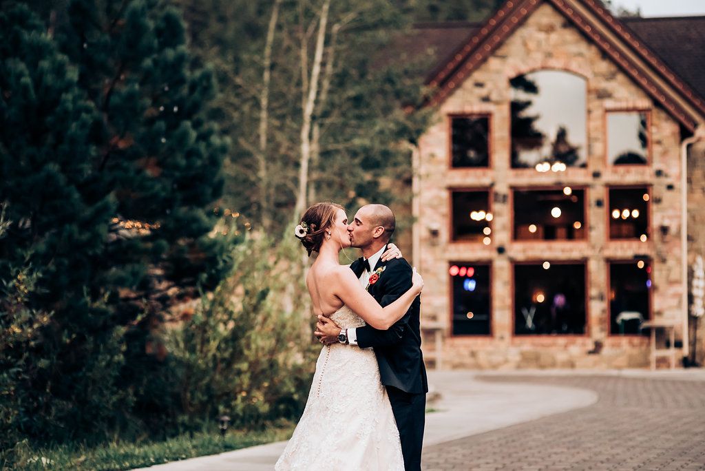 A romantic wedding dance outside a rustic lodge decorated with string lights.