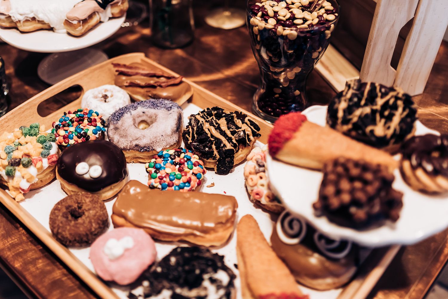 Collection of decorated donuts and pastries arranged on rustic wooden serving platters.