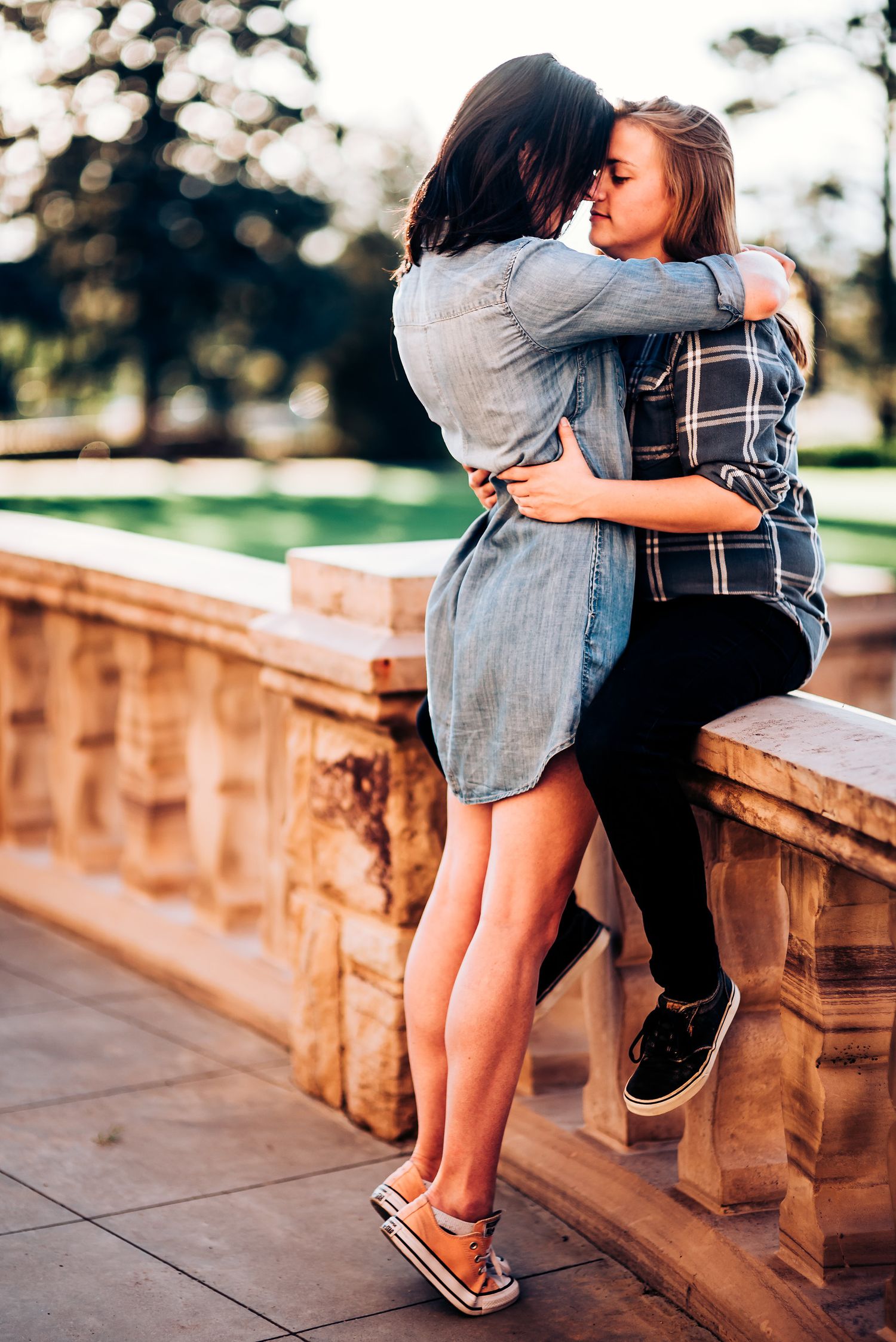 Intimate embrace on stone balustrade during golden hour.