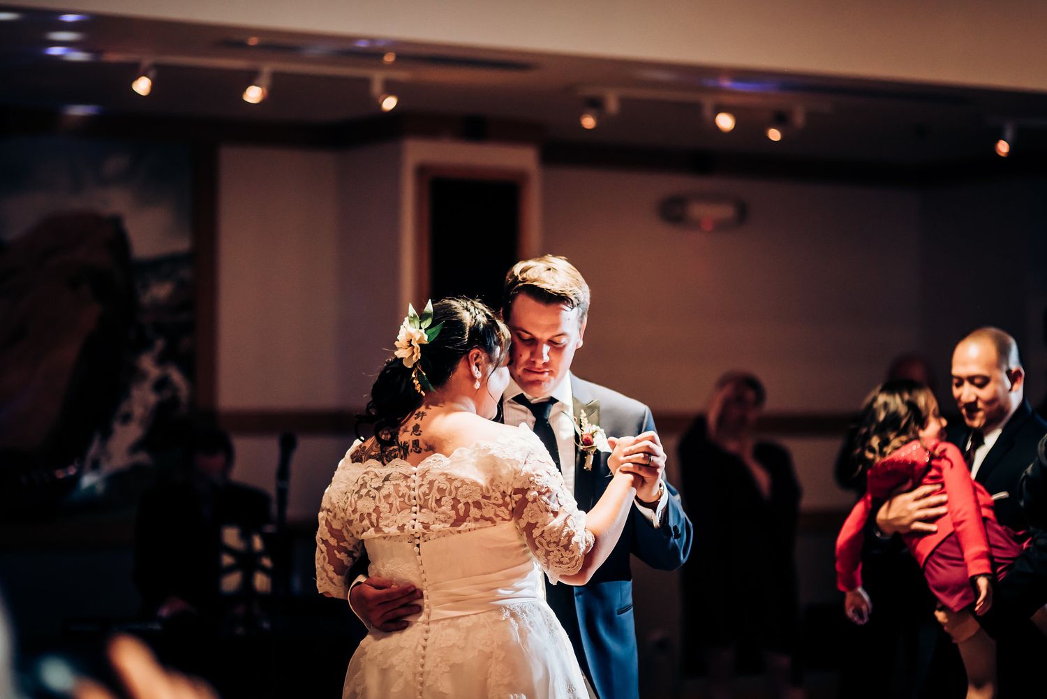 A romantic first dance between newlyweds at their wedding reception in a dimly lit ballroom.
