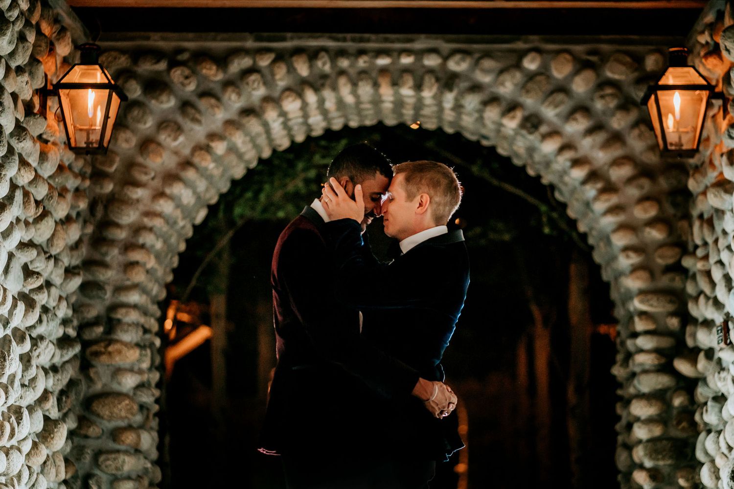 Intimate nighttime moment under a stone archway illuminated by lanterns.