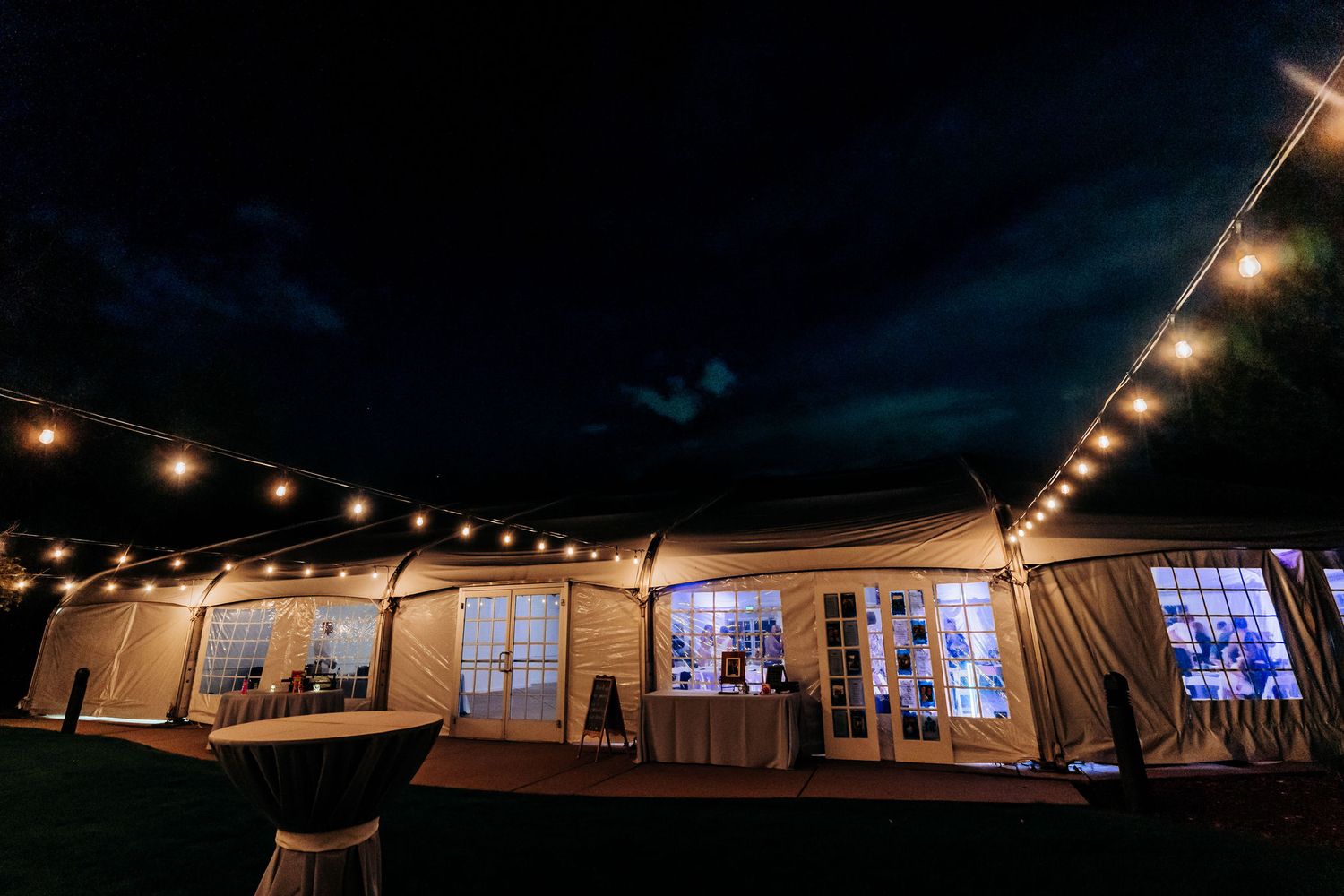 Wedding tent illuminated at night with string lights creating romantic ambiance.