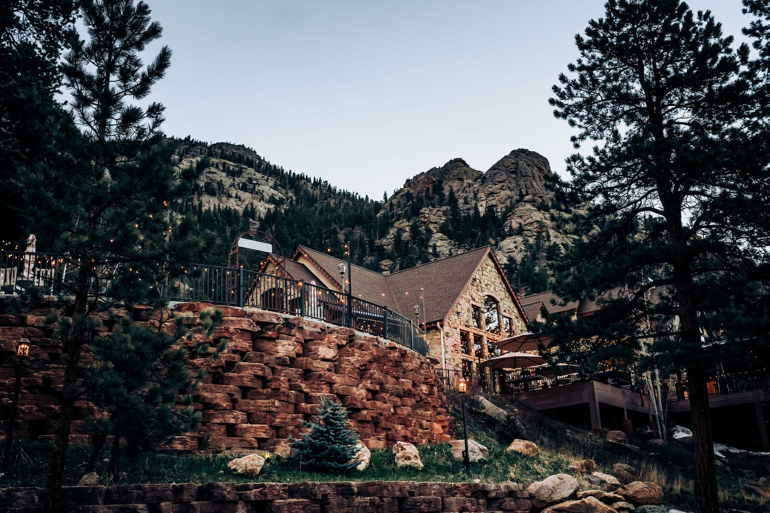 Mountain chapel venue nestled among pine trees with rustic stone architecture and dramatic rocky backdrop.