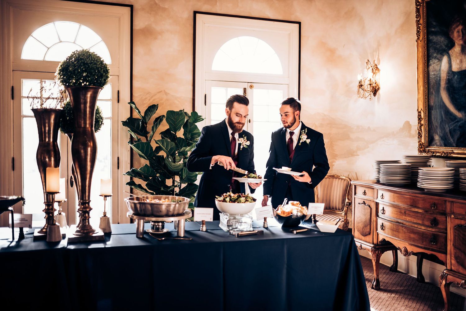 Two people manage a catering station at an elegant wedding reception with classical decor.