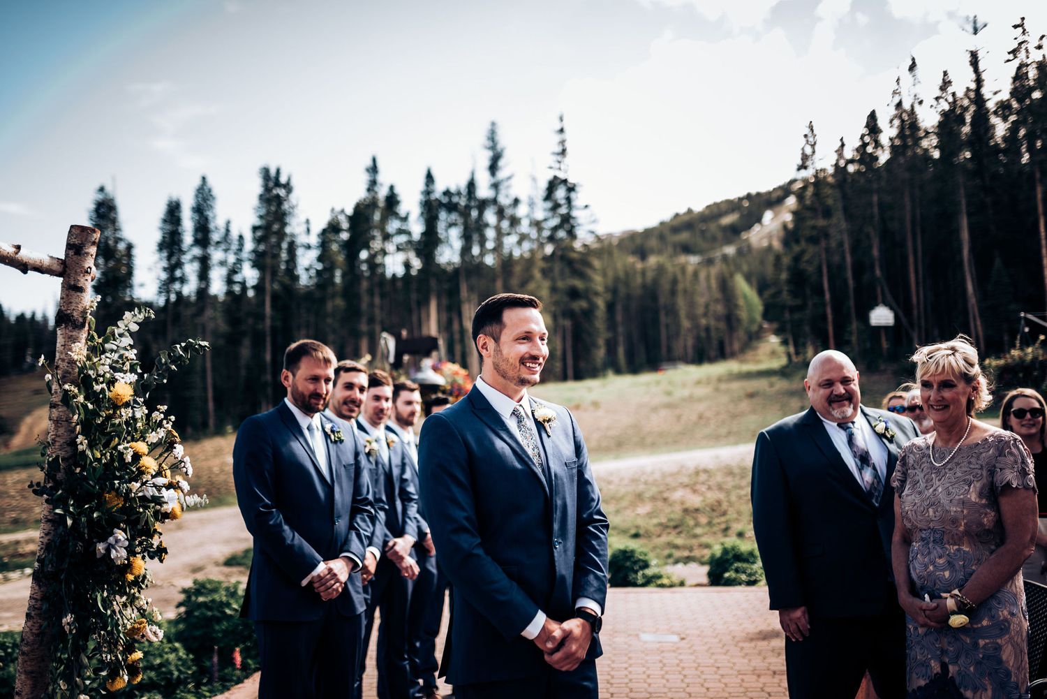 Groom and groomsmen sharing joyful moment during mountain wedding ceremony.