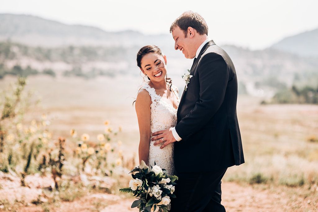Couple shares intimate moment while standing in scenic mountain landscape.