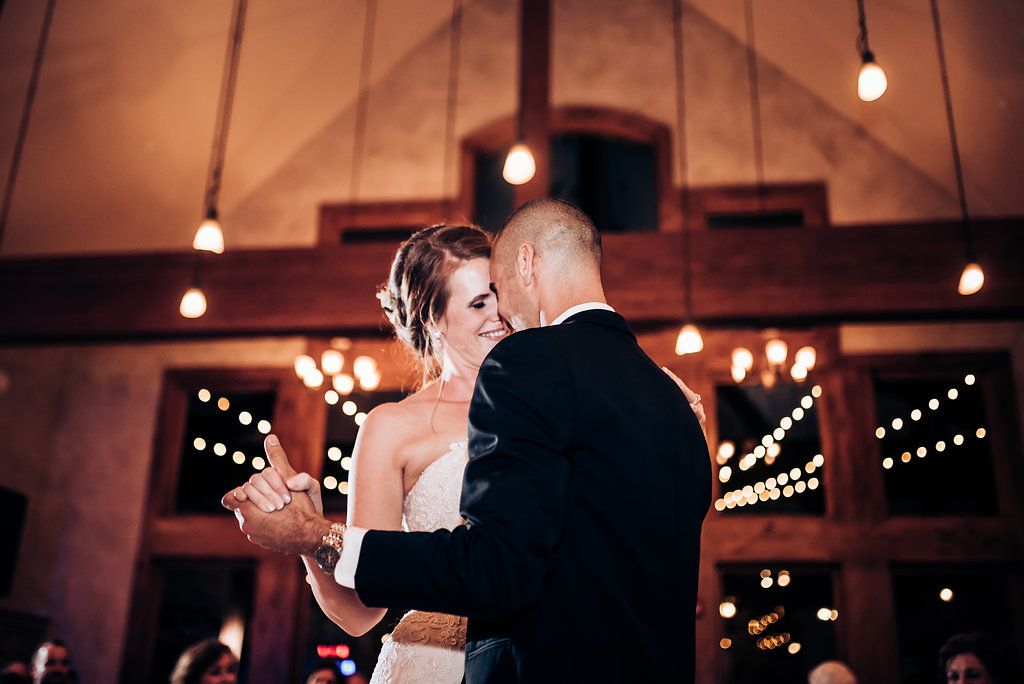Intimate dance moment between couple during evening wedding reception with ambient lighting.