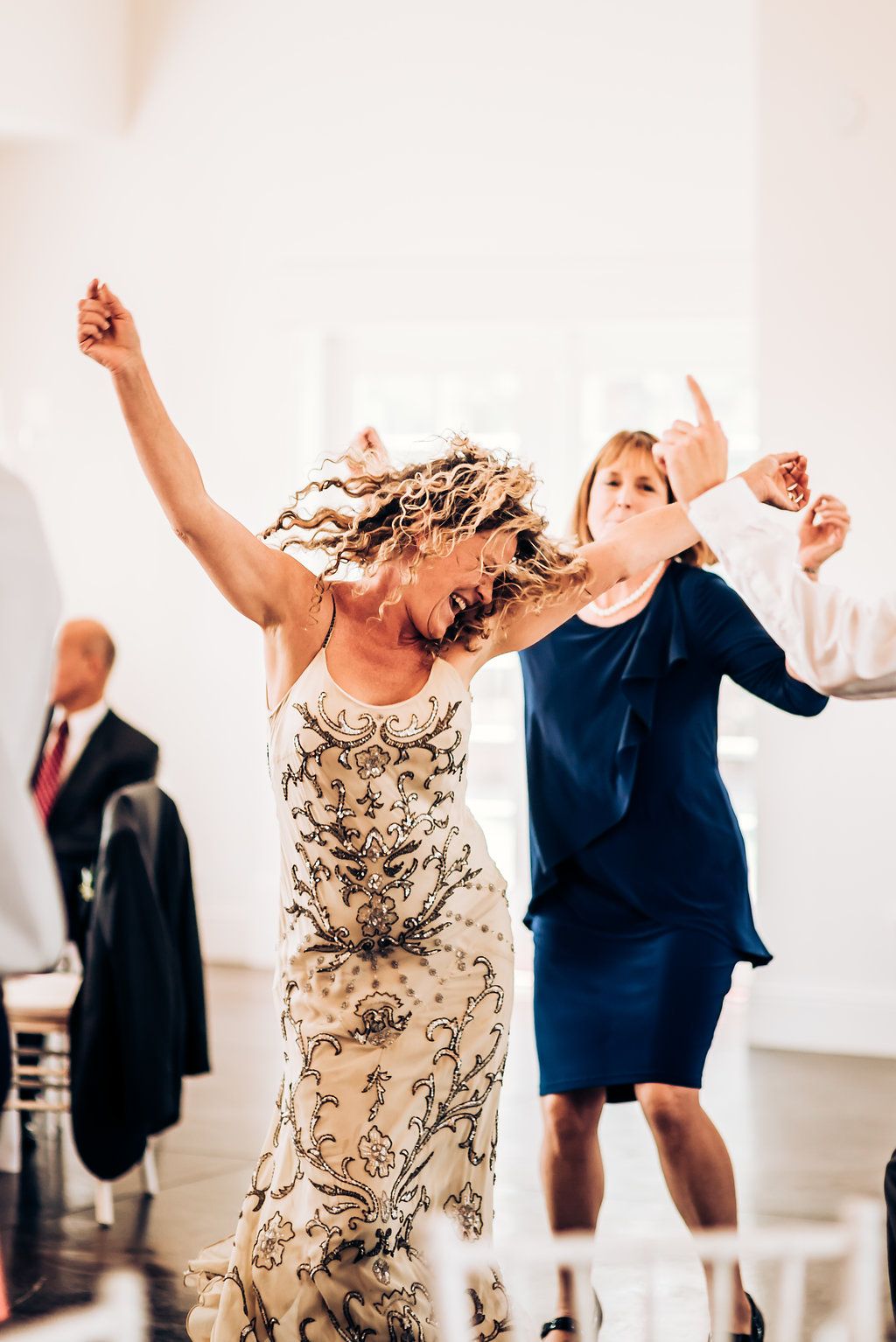 Two guests dancing energetically at a wedding reception in formal attire.