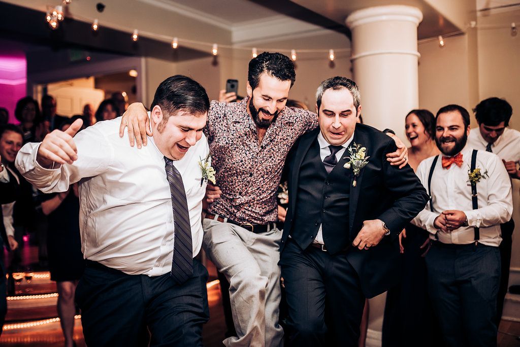 Energetic wedding guests dance and move together on the reception dance floor.