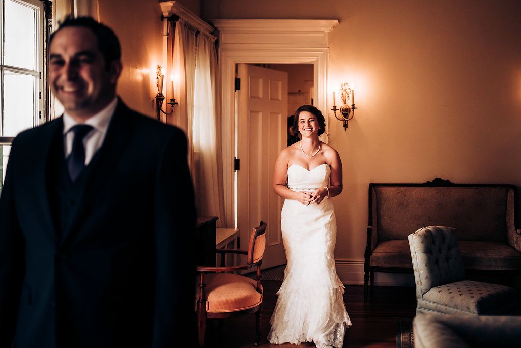 A wedding first look moment captured in an elegant hallway with warm lighting.