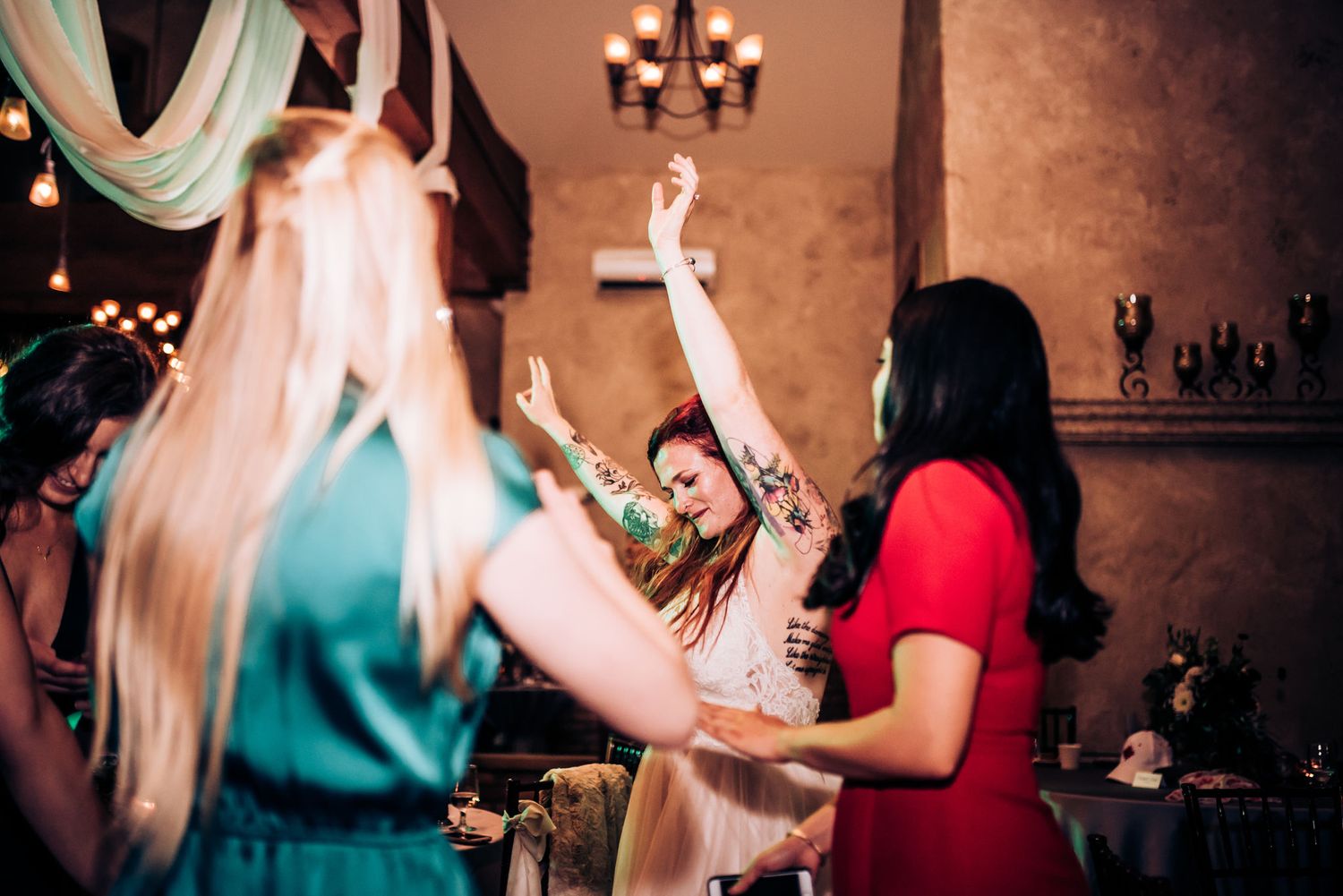 Enthusiastic party guests dancing and celebrating with raised arms at an indoor celebration.