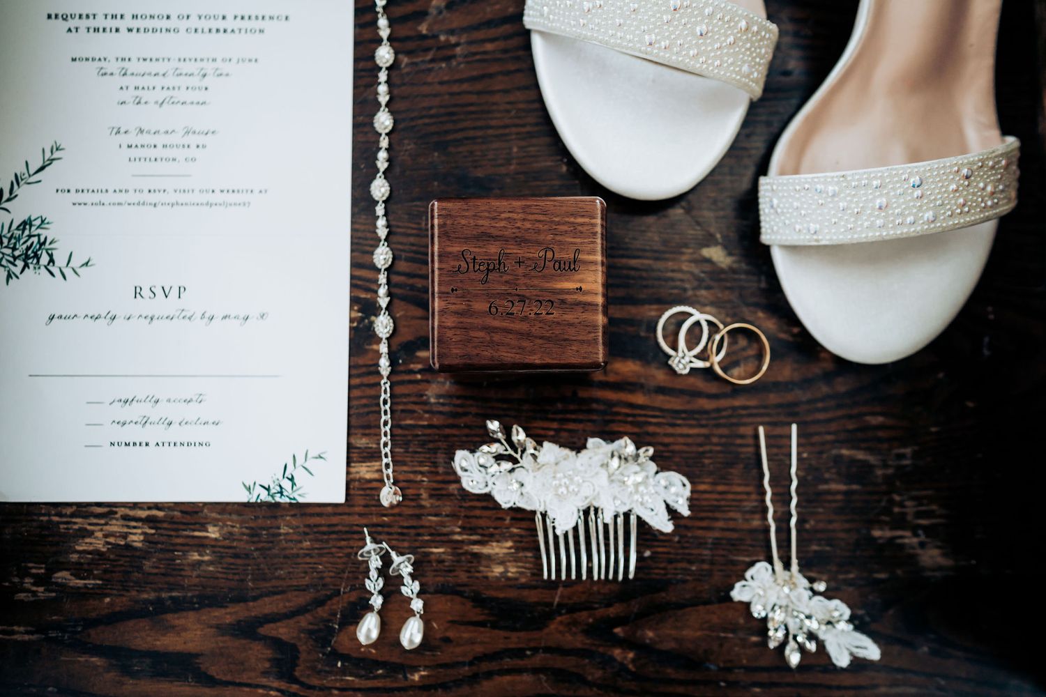 Wedding accessories including rings, shoes, and hair pieces arranged on rustic wooden surface.
