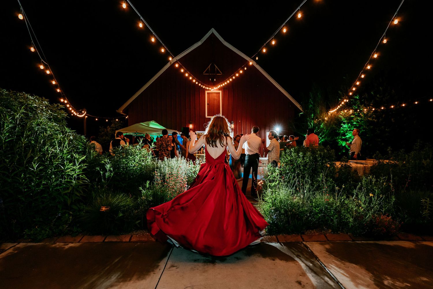 A dramatic evening dance scene with string lights and a flowing red dress on an outdoor patio.