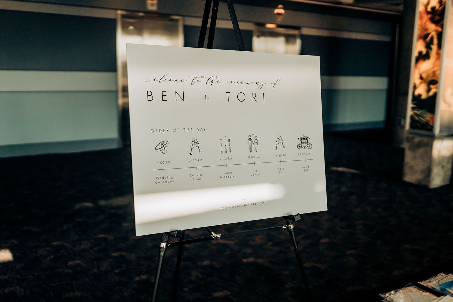 A wedding timeline sign displayed on an easel showing the day's schedule with cute stick figure illustrations.