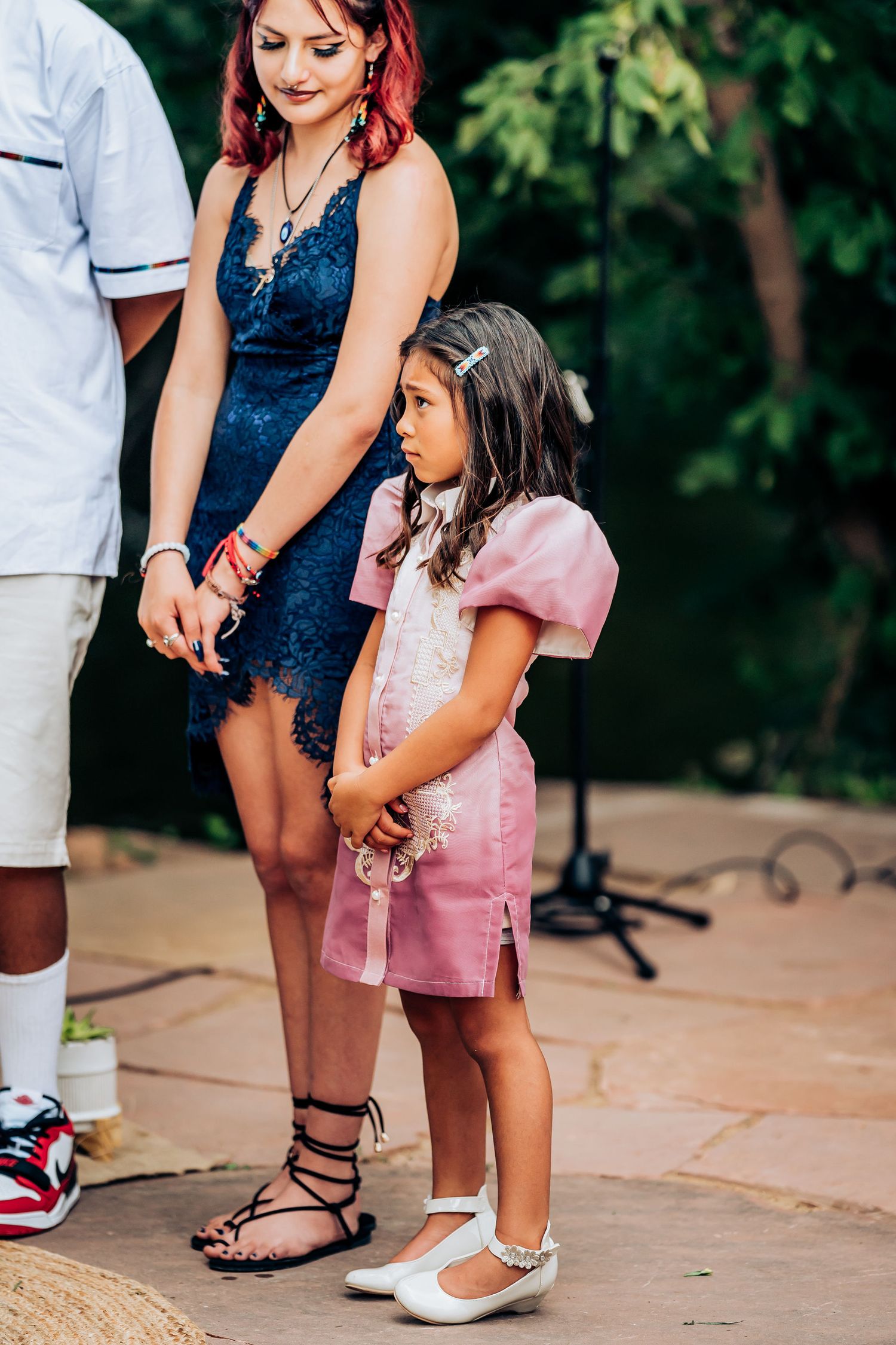 Close-up of contrasting outfits showing a navy blue dress and pink ensemble at an outdoor event.
