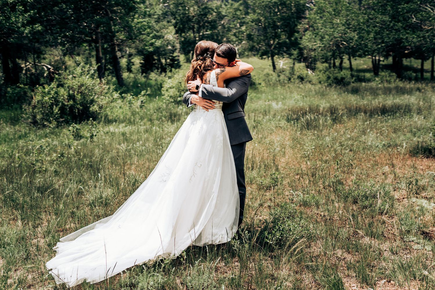 A wedding couple embraces in an intimate moment in a mountain meadow setting.