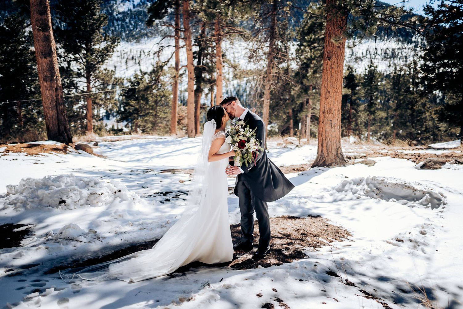 A romantic wedding moment captured in a snow-covered mountain forest.