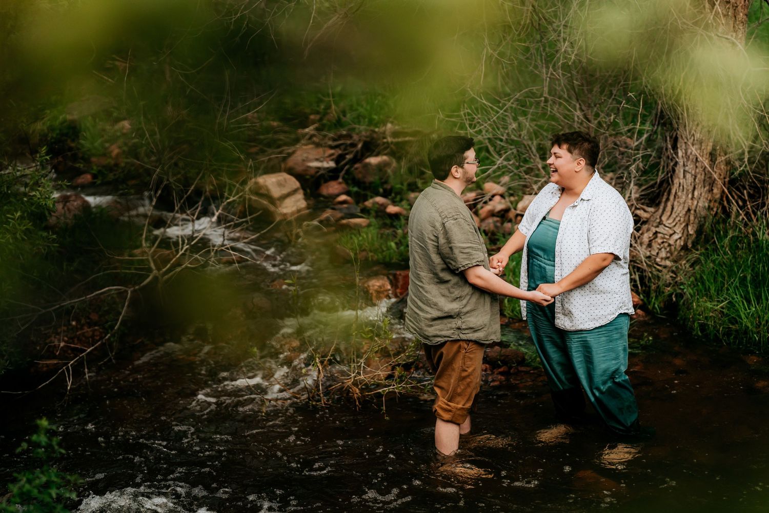 Wedding party enjoys casual moments by a natural stream or creek.