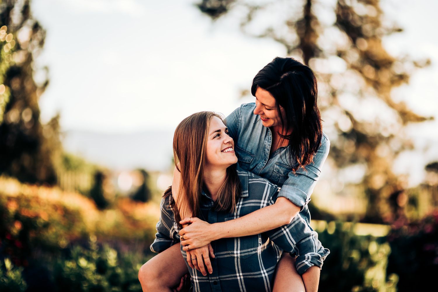 Joyful piggyback ride moment captured in outdoor setting with trees in background.
