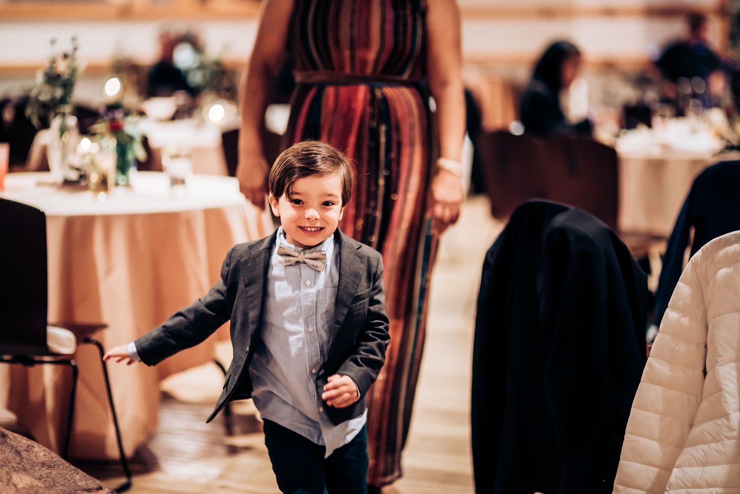 Young guest dancing enthusiastically at an indoor reception venue with tables in background.