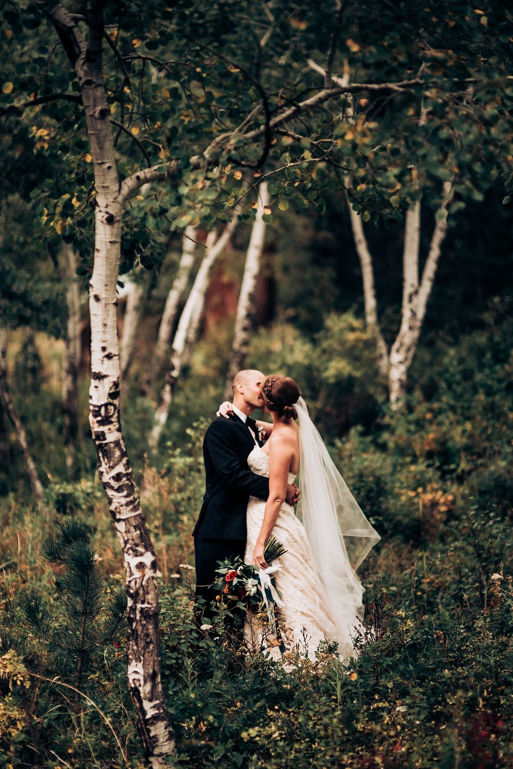 Romantic wedding portrait among birch trees in a woodland setting.