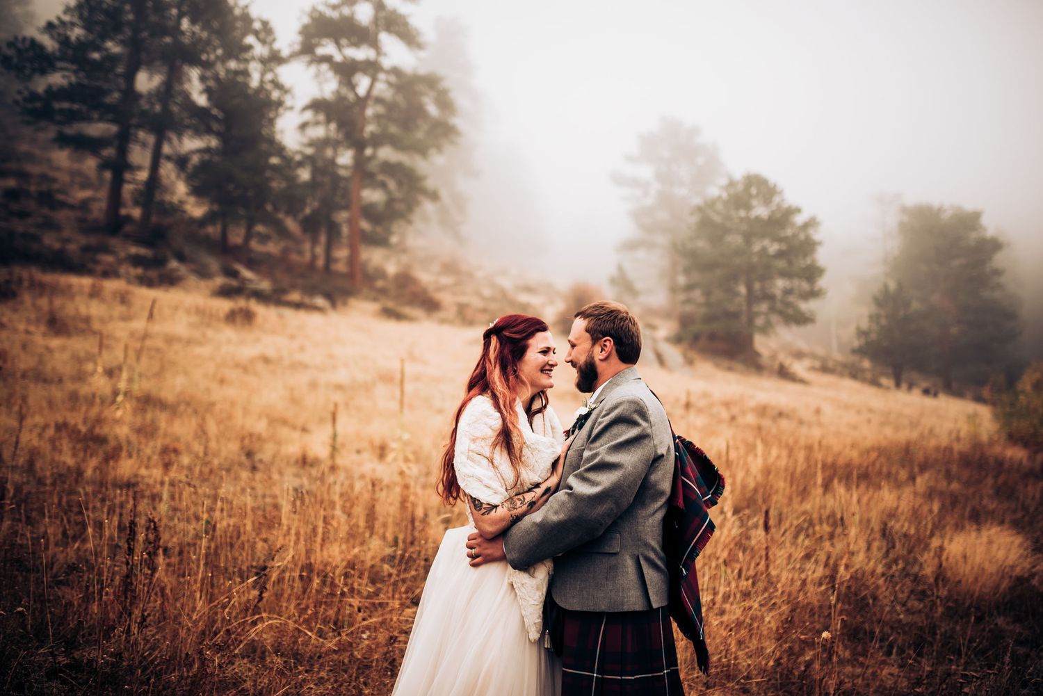 Intimate wedding portrait in golden mountain meadow with traditional Scottish attire.