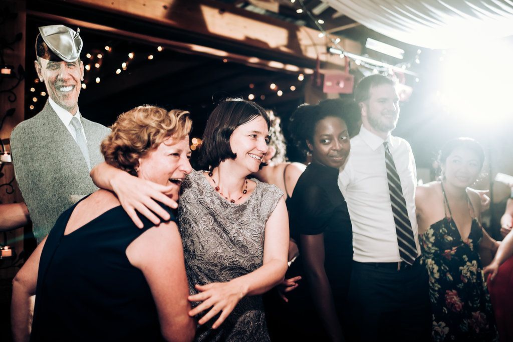 Guests share joyful moments together under string lights at an indoor celebration.