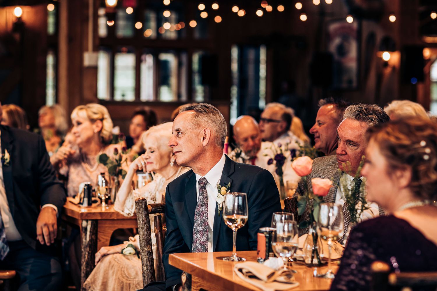 Formal dinner guests seated at tables listen attentively during speeches.