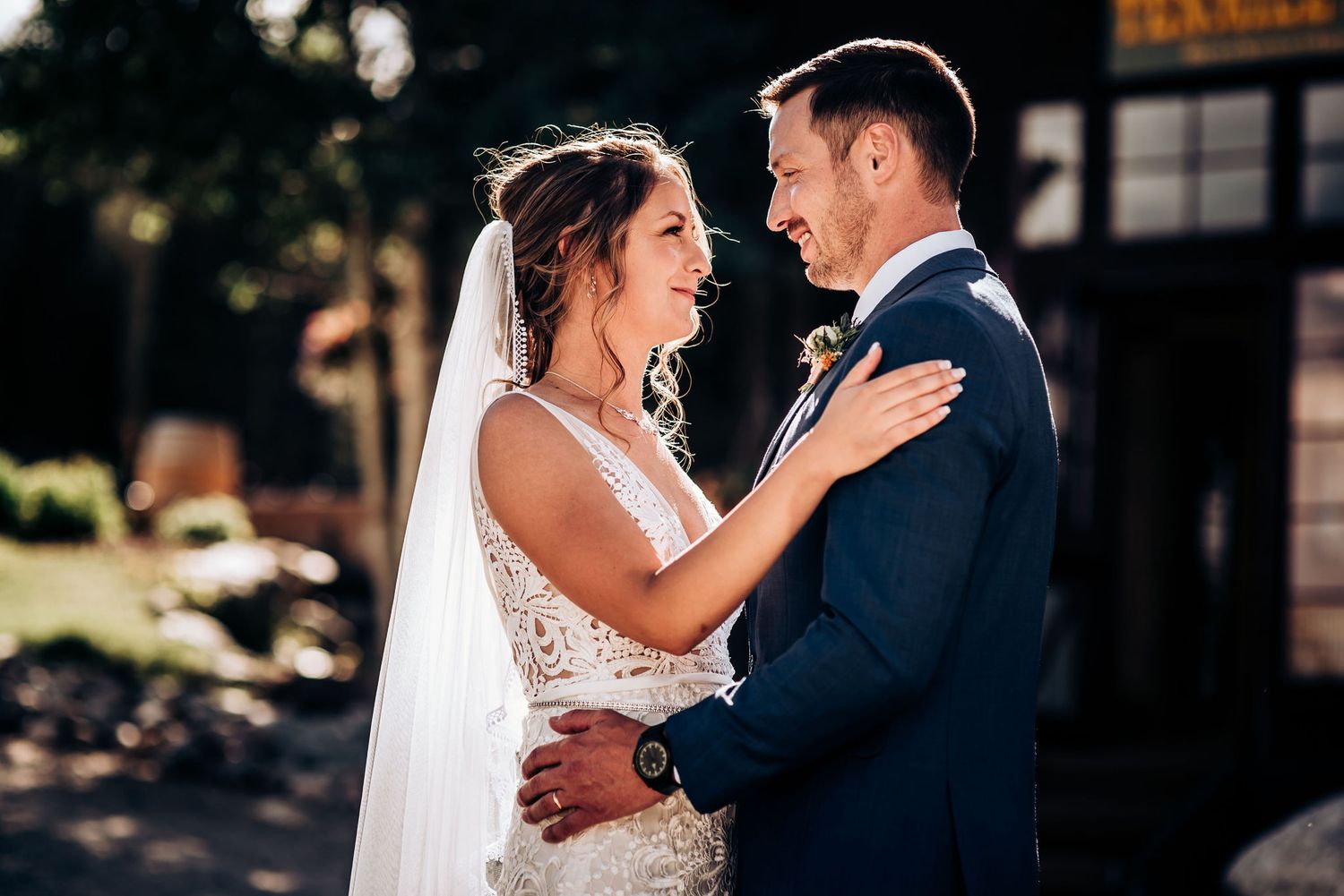 Intimate wedding moment captured in warm sunlight with mountain backdrop.