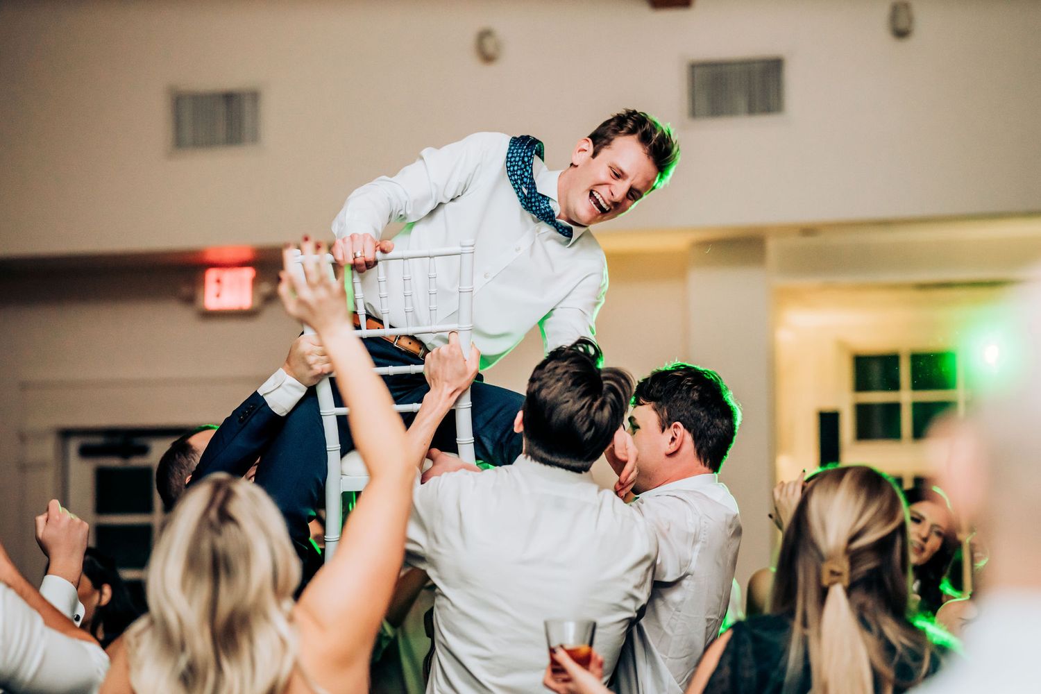 Wedding guests lift and celebrate during an energetic reception dance party moment.