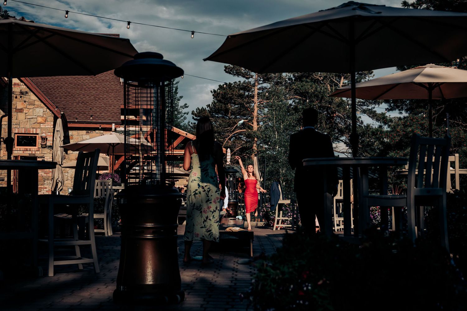 A rustic outdoor venue with wooden buildings and umbrellas at dusk.