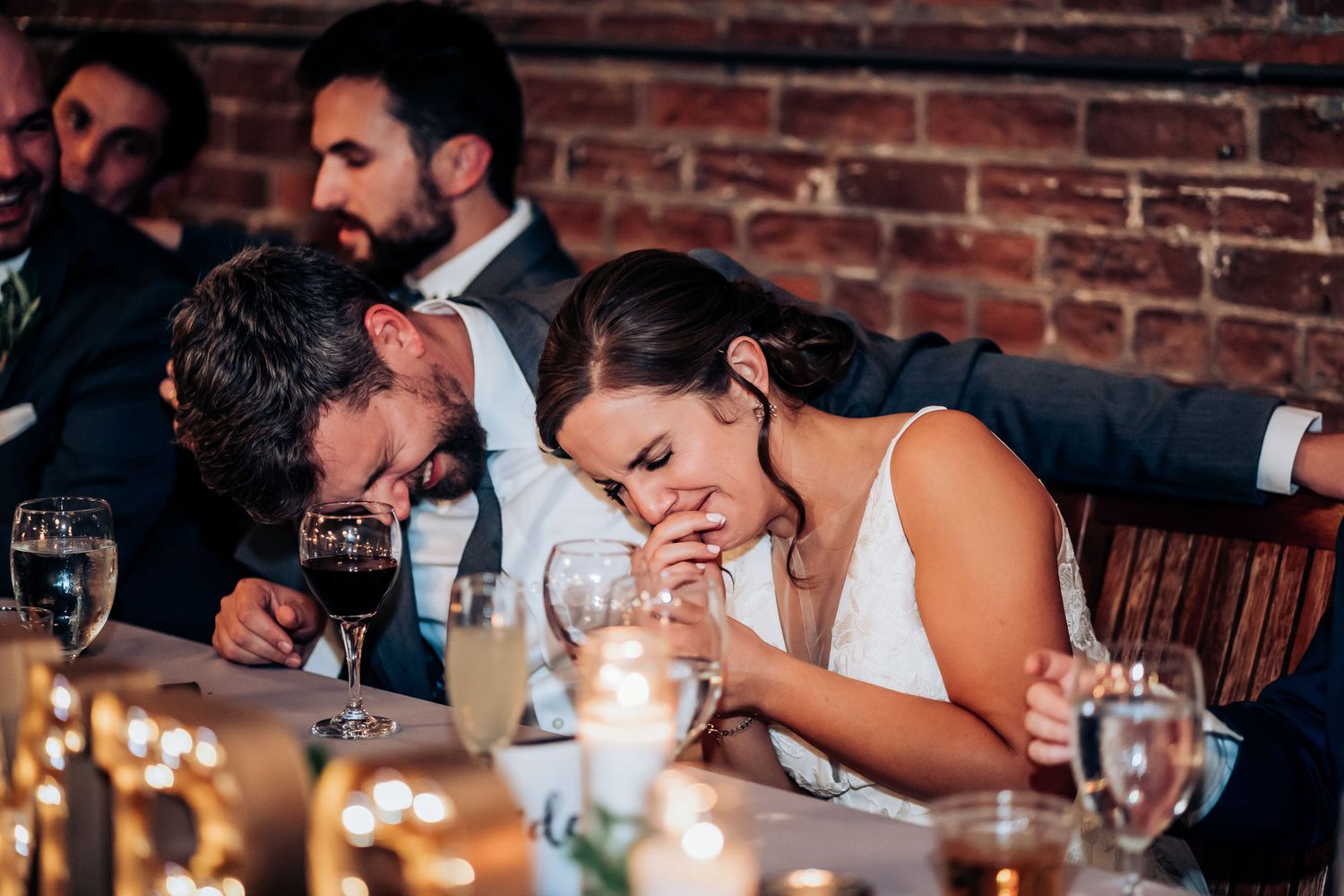 Emotional moment captured during wedding reception speeches at decorated head table.