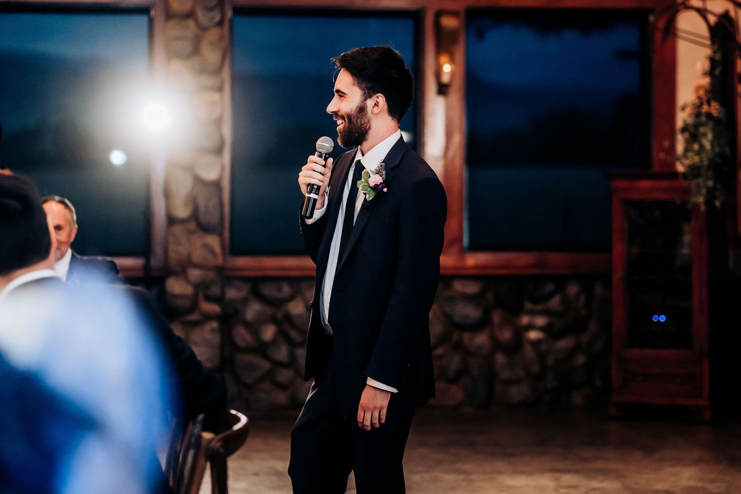 Wedding speech being delivered in rustic stone venue during evening reception.