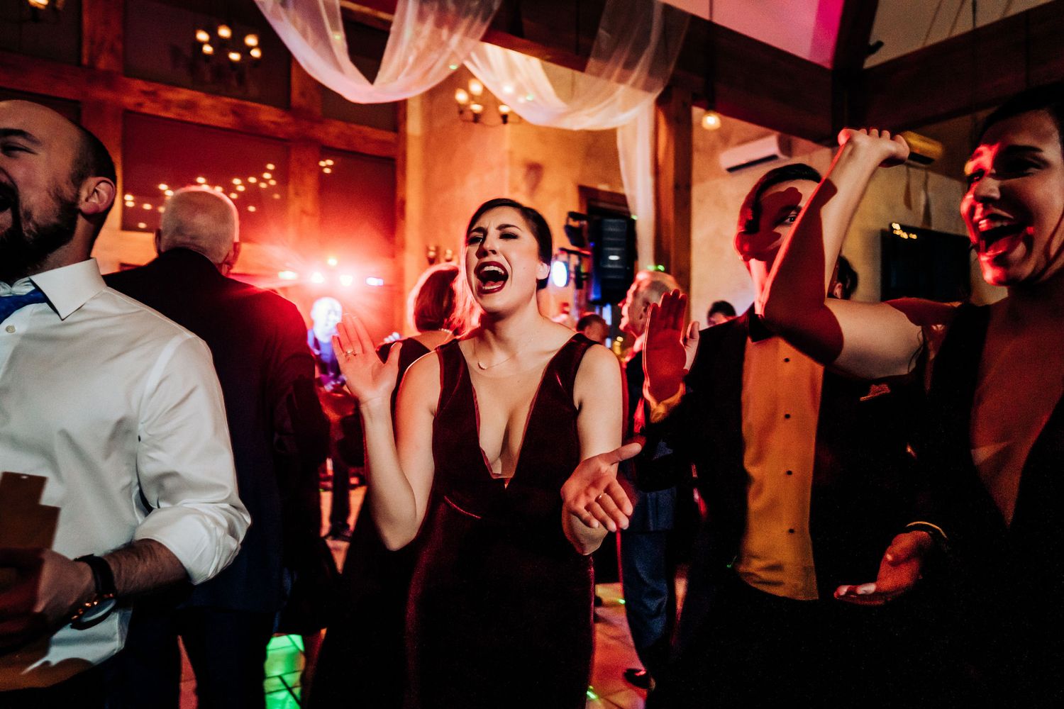 Guests dancing and celebrating with enthusiasm at a dimly lit indoor party venue.