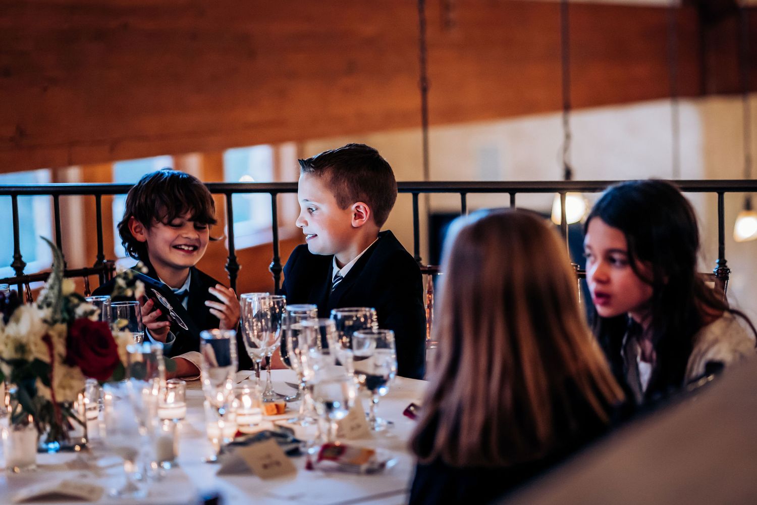 Wedding reception guests enjoying dinner conversation at an elegantly set table.