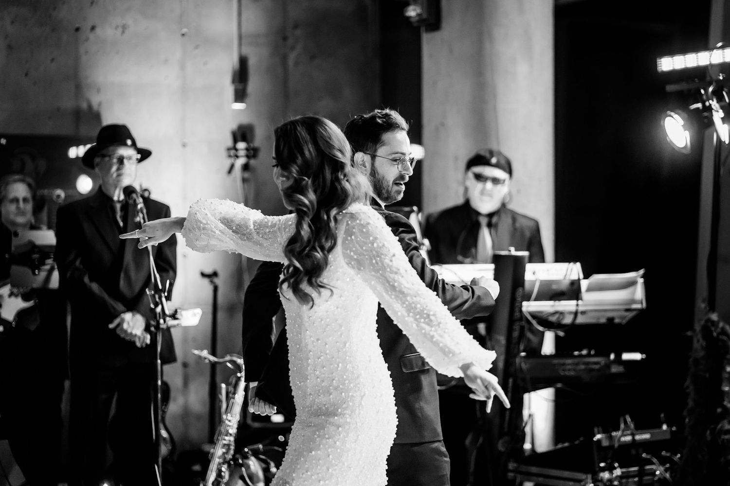 A couple dances together in black and white with a live band performing behind them.
