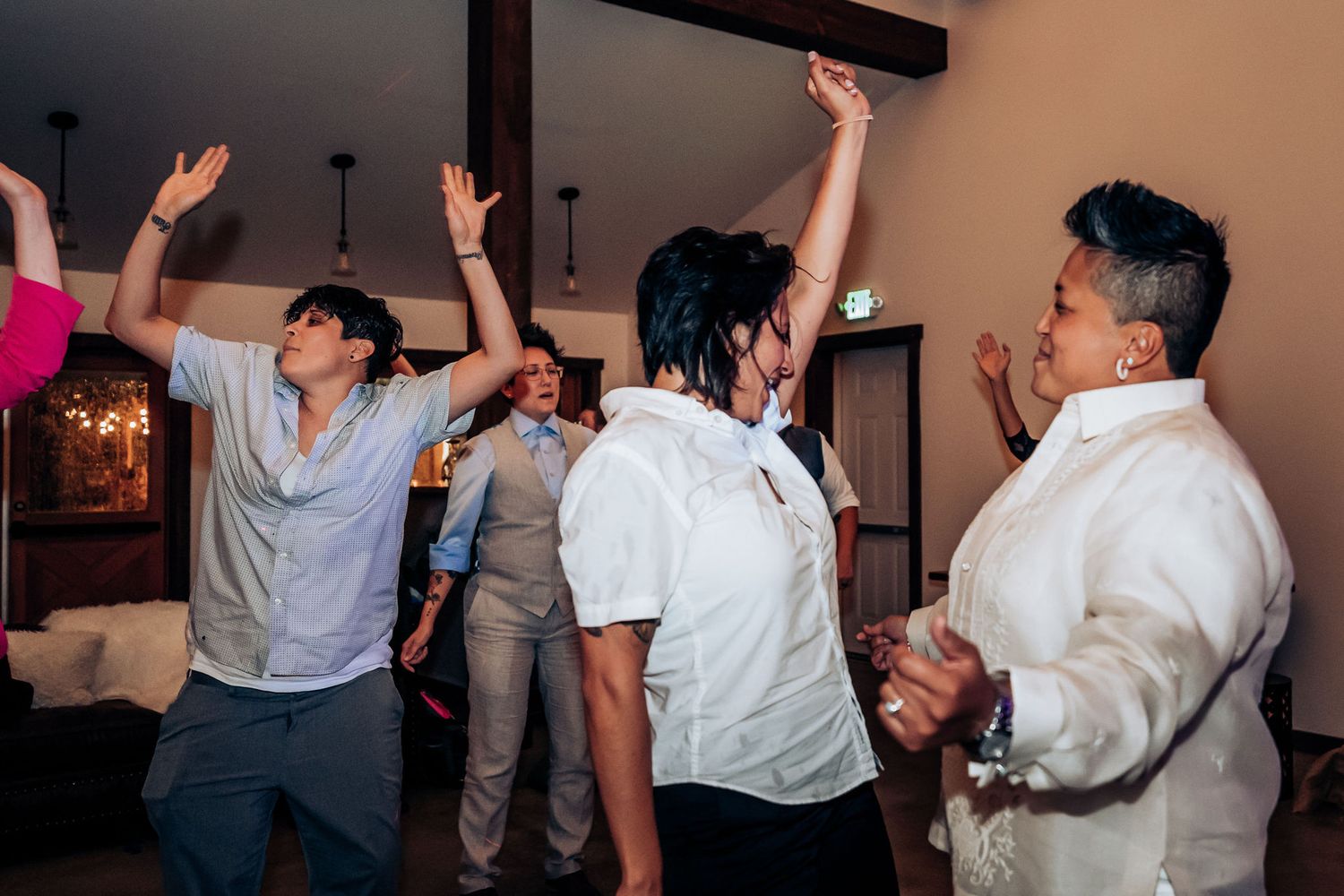 People celebrating with raised arms and dancing at an indoor party.