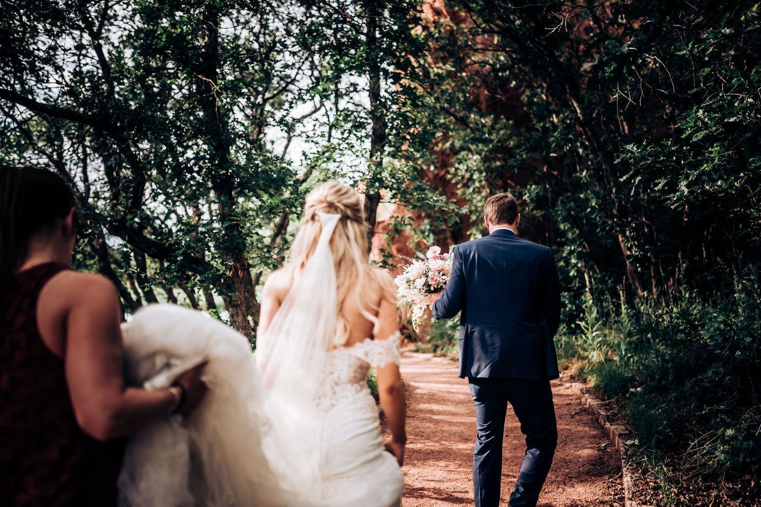 Wedding party walking up garden path surrounded by lush greenery.