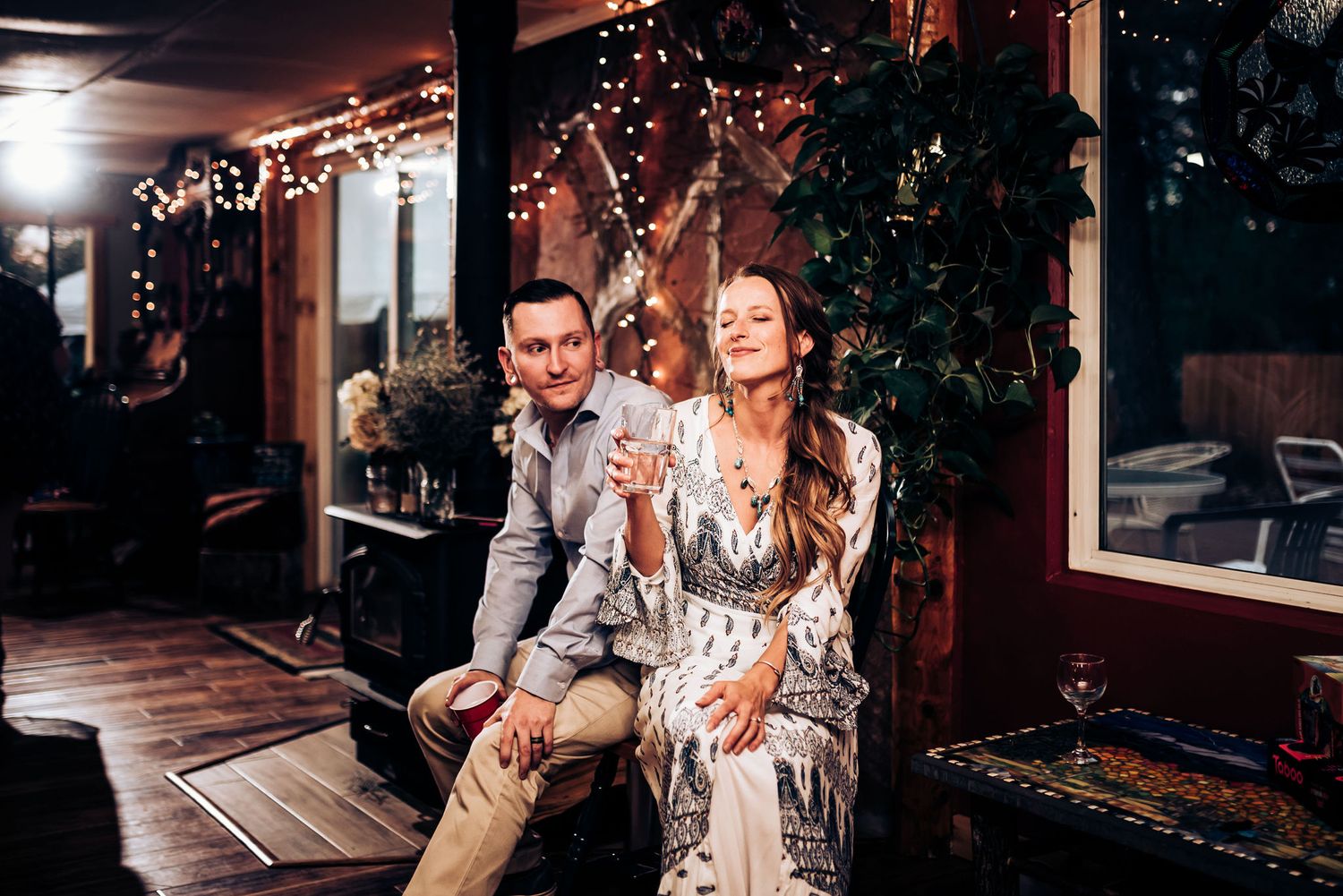 People sit together on porch with string lights creating warm ambiance.