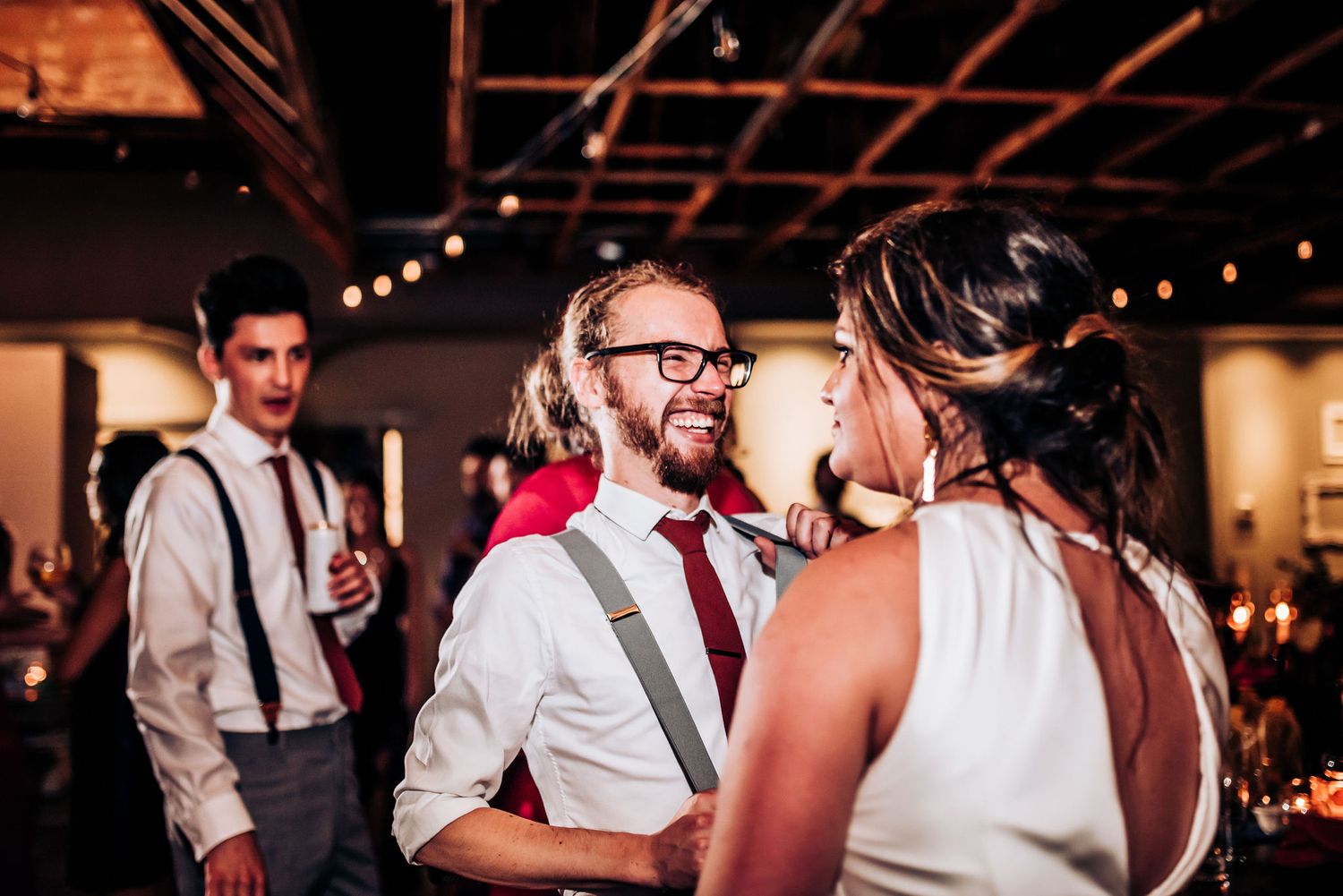 Romantic dance moment captured at wedding reception with exposed brick walls and overhead lighting.
