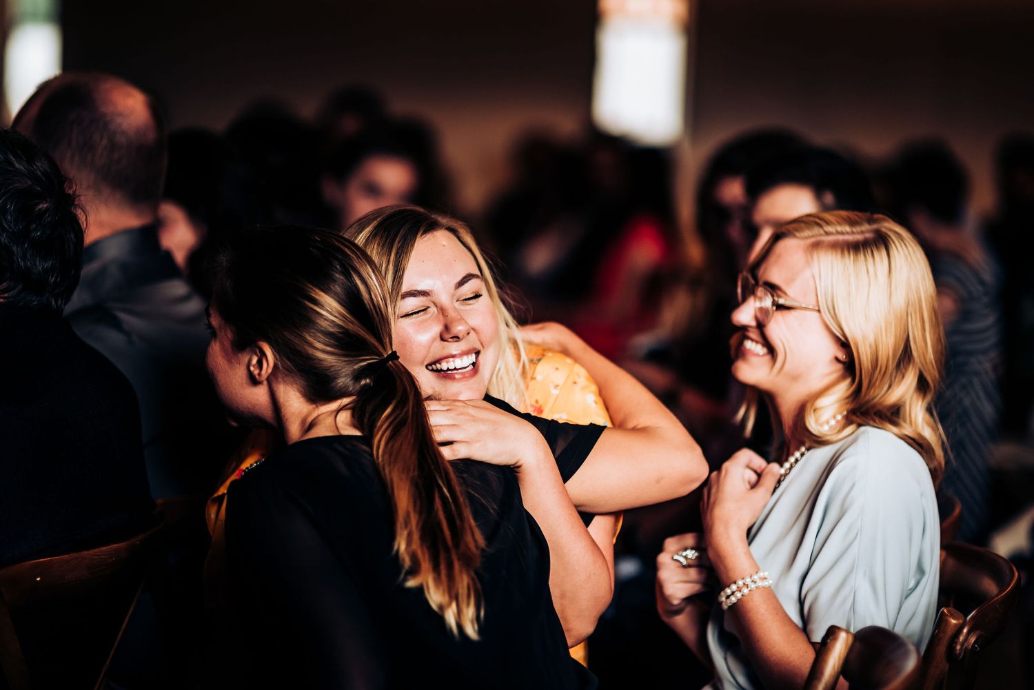 Wedding guests share joyful laughter during reception celebration.
