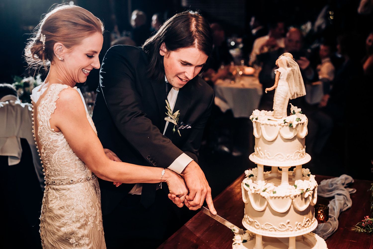 Couple cuts their traditional white tiered wedding cake together at their reception.