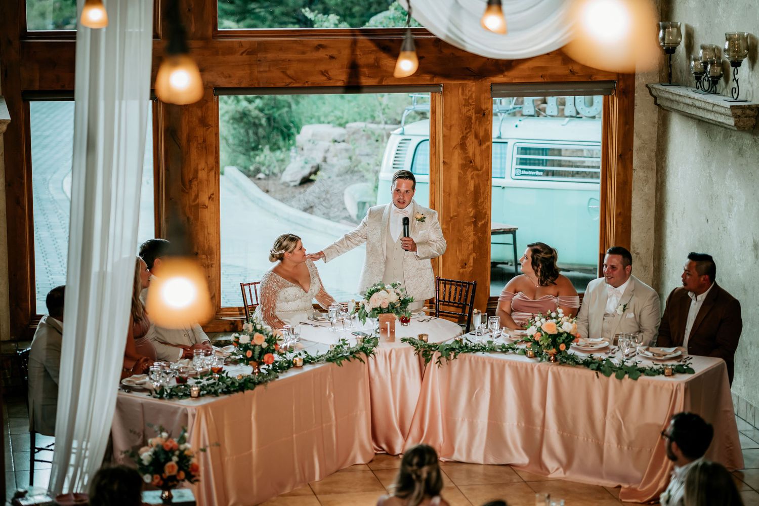 Reception dinner setup in rustic wooden venue with warm lighting and pink table decor.